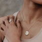 A close up of a lady wearing a fingerprint impression necklace and ring. 