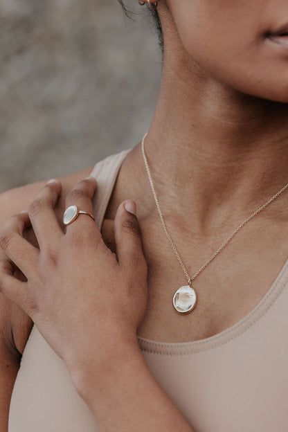 A close up of a lady wearing a fingerprint impression necklace and ring. 
