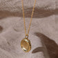 A yellow gold fingerprint impression pendant hangng over natural linen.
