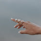 An artistic photo of a lady's hand with three impression rings displayed on her finger, in silver, yellow gold and rose gold. 