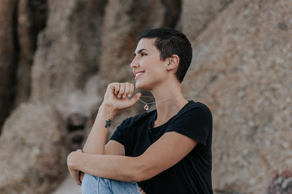 A lady wearing a gold fingerprint impression pendant and playfully holding the chain in her hand. 