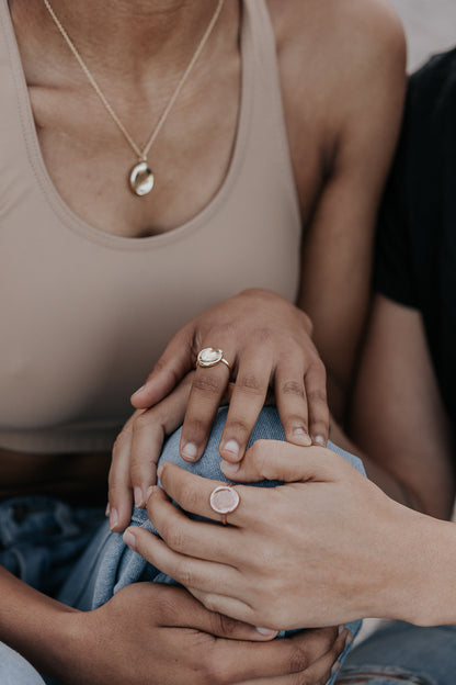 A close-up of two ladies, showing them both wearing a fingerprint impression ring and the one wearing an impression necklace.